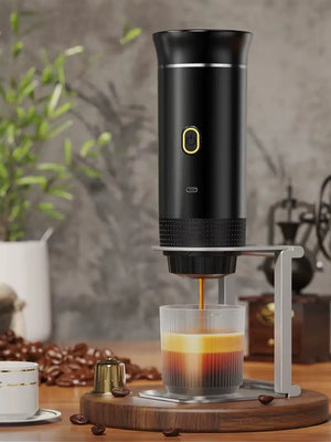 Black NomadBarista espresso maker on a stand, pouring a shot into a clear cup, with a capsule and coffee beans