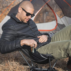 Man resting in an ultralight chair outside a tent