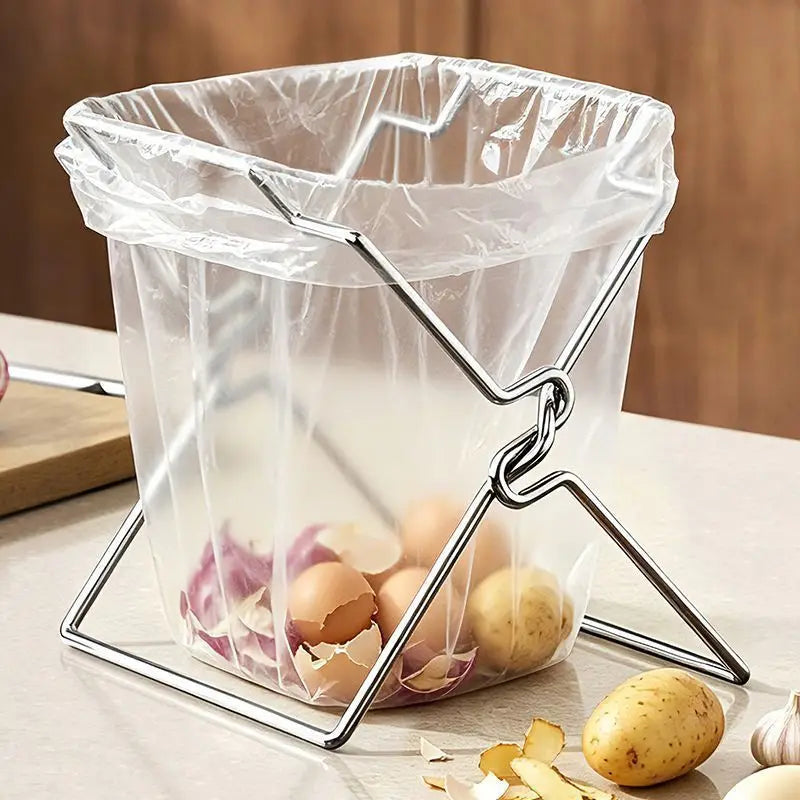 Foldable stainless steel bag holder with clear bag of potato and onion peels on a kitchen counter