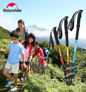 Family hiking on a green mountain trail, with three trekking poles in red, orange and blue
