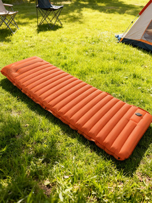Orange pad on the grass beside a tent
