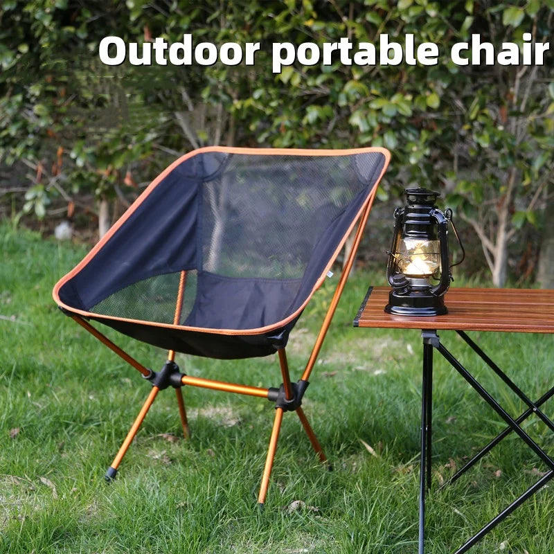 Mesh moon camping chair with orange trim by a lantern