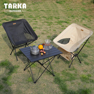 Black and beige moon chairs at a camp table on the grass