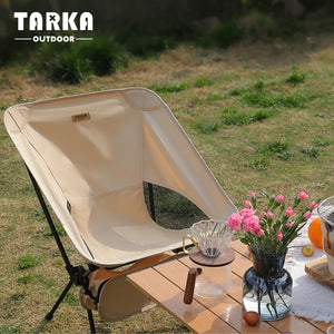 Beige moon chair outdoors next to a table with flowers