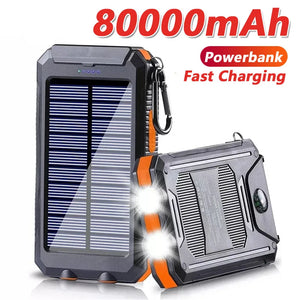 TrailCell solar power bank in orange and black with carabiner, dual flashlights lit and compass on back