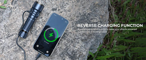 Flashlight charging a phone by cable on a rock