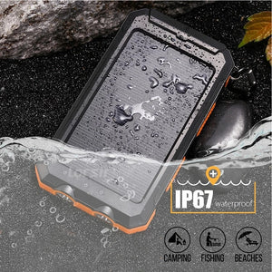 Wet orange TrailCell solar power bank half in water on dark stones