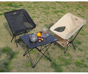 Two moon chairs, black and beige, with a camp table