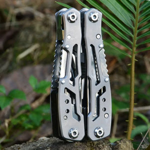 Silver Adventure Buddy multi-tool standing closed on a log beside a fern