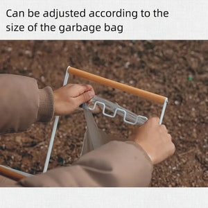 Hands hooking a bag onto the wavy wire hooks of a white trash bag stand