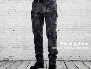 Black python print cargo pants worn in front of a white brick wall