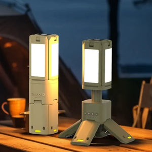 Two green telescopic camping lights on a wood table at camp, one folded shut, one open on its tripod