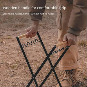 Hands opening the black X-frame trash bag stand by its two wood handles