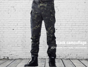 Black camouflage Adventure Ready cargo pants worn in front of a white brick wall