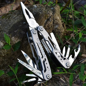 Large silver Adventure Buddy multi-tool open on a rock with pliers and fold-out tools spread