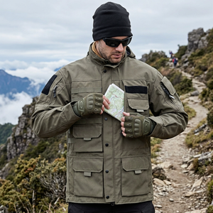 Man on a mountain trail in an army green hooded tactical jacket, tucking a map into a chest pocket