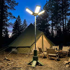 Green telescopic camping light on a tripod with fold-out panels lighting a tent at dusk