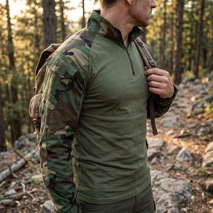 Hiker wearing the StealthWeave shirt in Woodland Camo: olive body, camo sleeves, quarter zip, sleeve pocket
