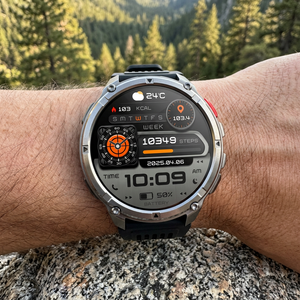 TrailCore smartwatch with all-black band on a wrist resting on granite, time and compass on screen