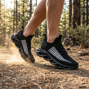 Black TrailHawk running shoes with white side stripes and wavy soles mid-stride on a dirt trail in the pines