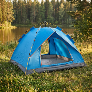 Blue pop-up camping tent set up with the door open in a grassy clearing beside a forest lake