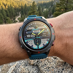 SummitNav GPS smartwatch with a teal-blue silicone band on a wrist at a trail overlook