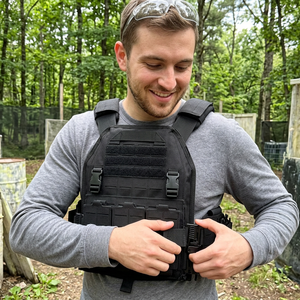 Player buckling the black quick-release airsoft vest with laser-cut MOLLE panels at an outdoor field