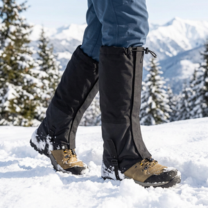 Black DriftPeak leg gaiters over hiking boots stepping through deep snow on a mountain trail