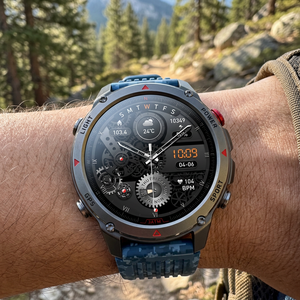 SummitNav GPS smartwatch with a blue camouflage silicone band on a wrist near a mountain trail