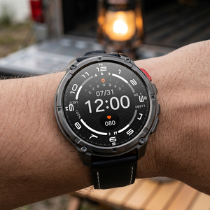 TrailCore outdoor smartwatch with a black leather band on a wrist at a lakeside campsite at dusk