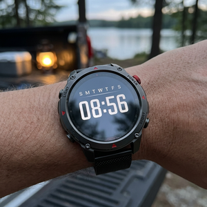 SummitNav GPS smartwatch with a black mesh band on a wrist at a lakeside campsite