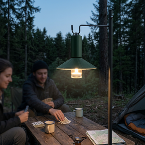 EmberCone rechargeable lantern with shade glowing warm white over friends playing cards at camp