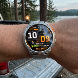 TrailCore outdoor smartwatch with a silver steel flat-link bracelet on a wrist at a lakeside campsite