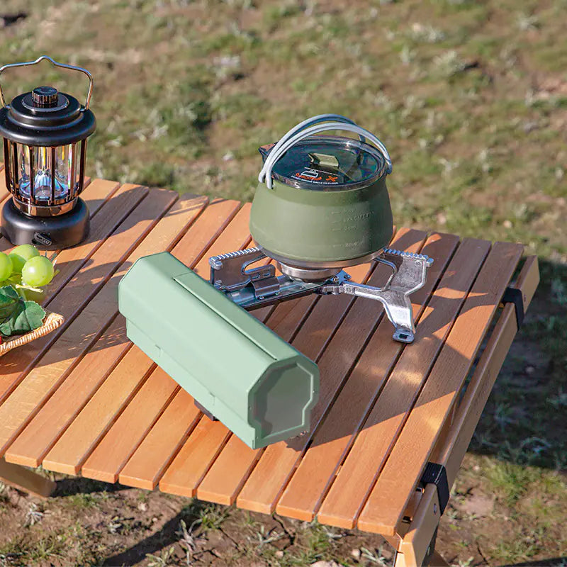 Green AdventureChef stove heating a green kettle on a wooden camp table